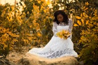 一名身穿白色连衣裙的女子，在生机勃勃的秋叶间优雅地摆出姿势