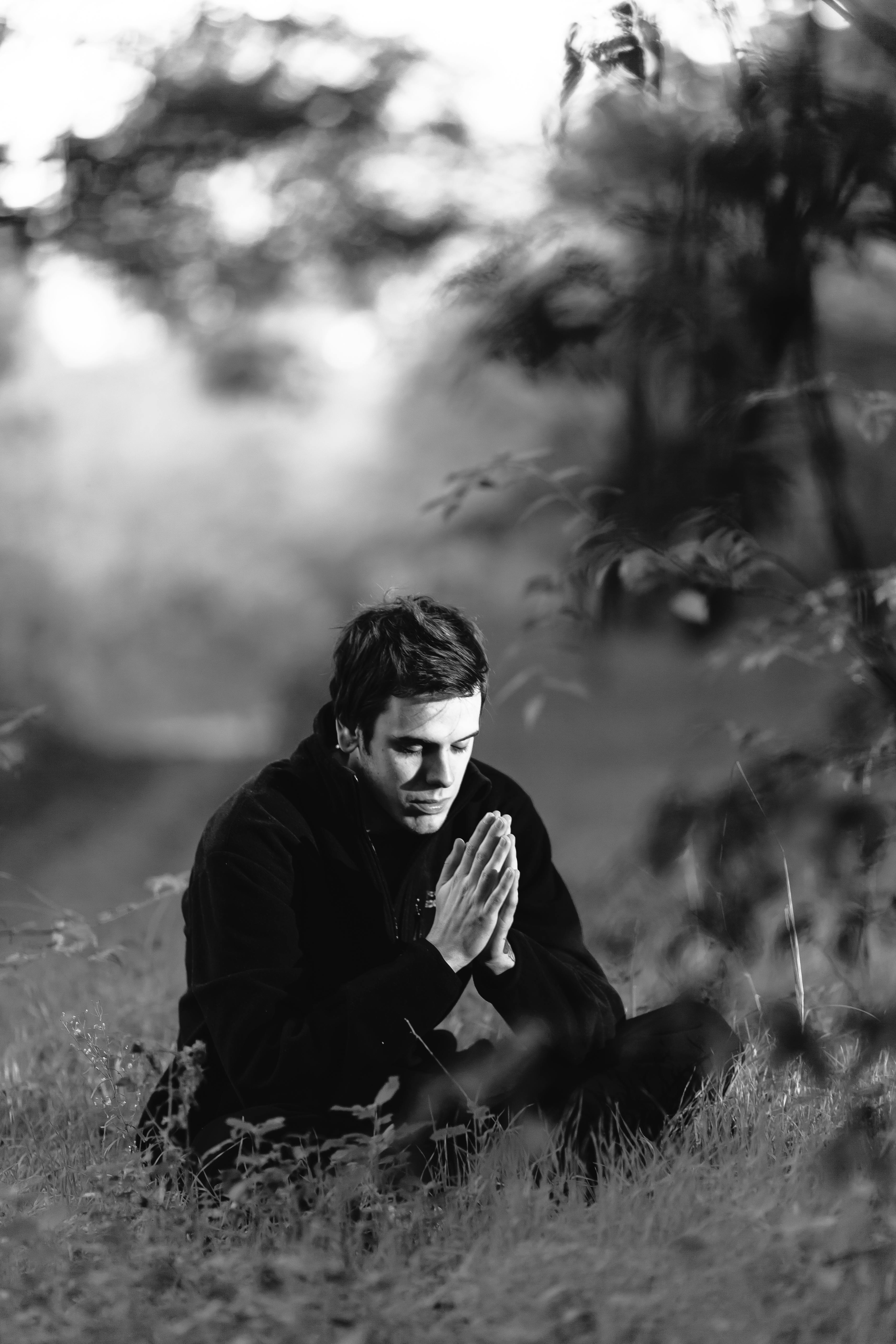 Free Grayscale Photography of Man Sitting on Grass Field Stock Photo