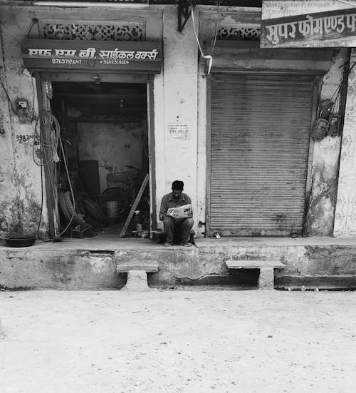 Free stock photo of city street, man on street, man reading news