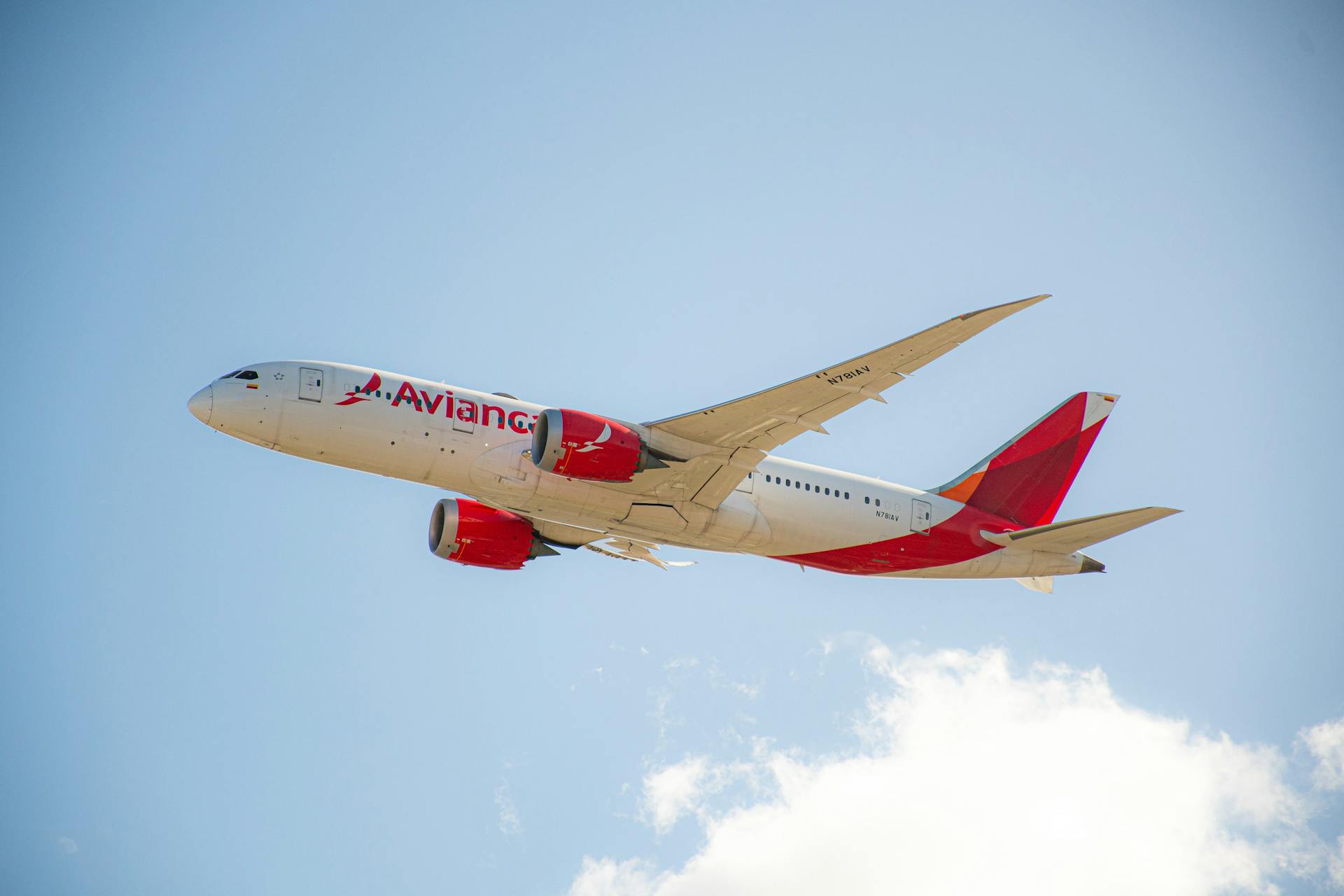 Avianca passenger jet flying under a clear blue sky, showcasing flight travel.