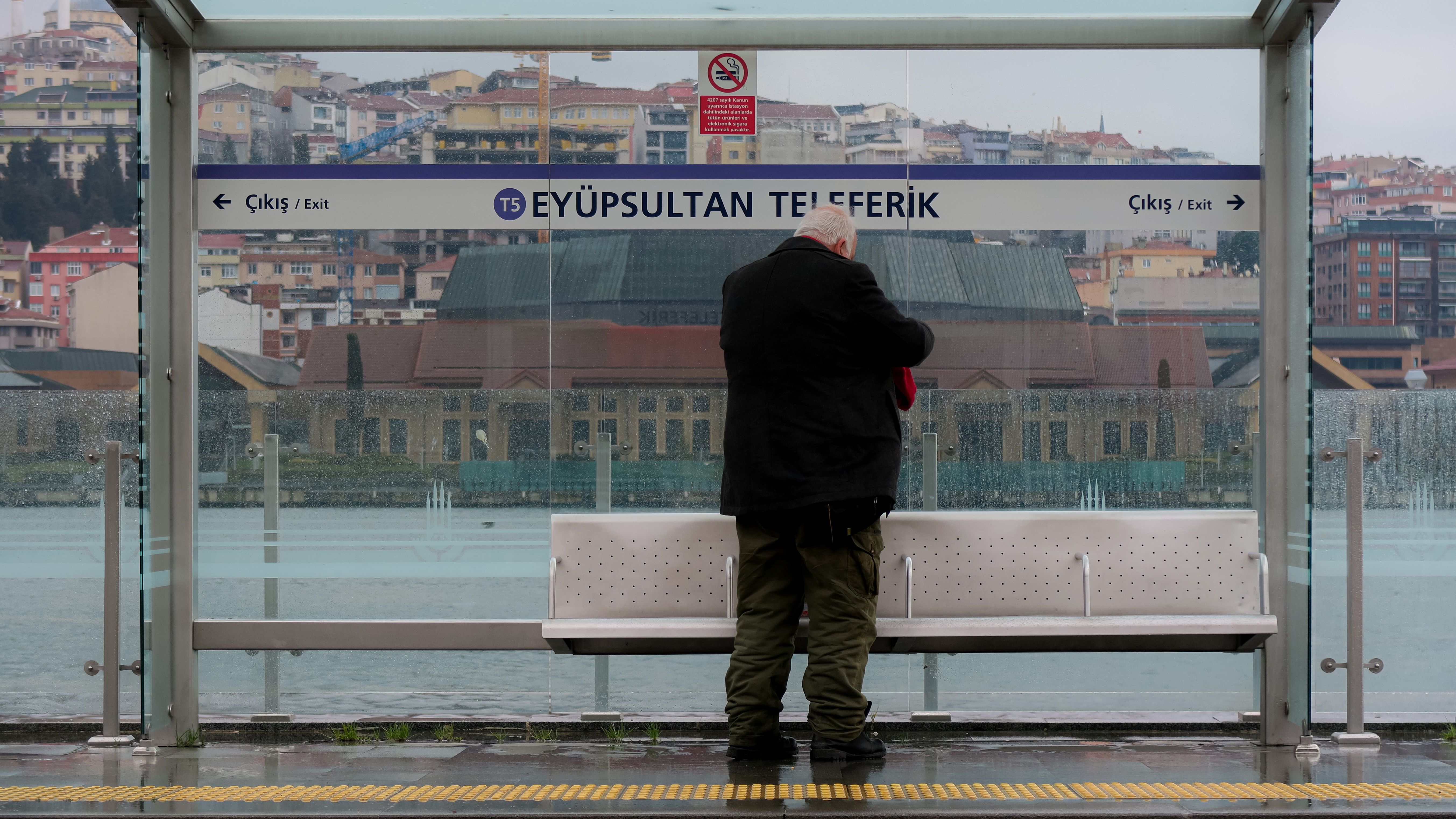 Man waits at Eyüp Sultan Cable Car Station in Istanbul, reflecting urban life.