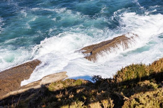 Dynamic waves crash against a rocky coastline, showcasing nature's raw beauty and power.
