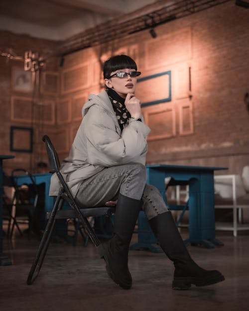 Young Fashionable Woman Wearing Sunglasses Sitting on a Chair 