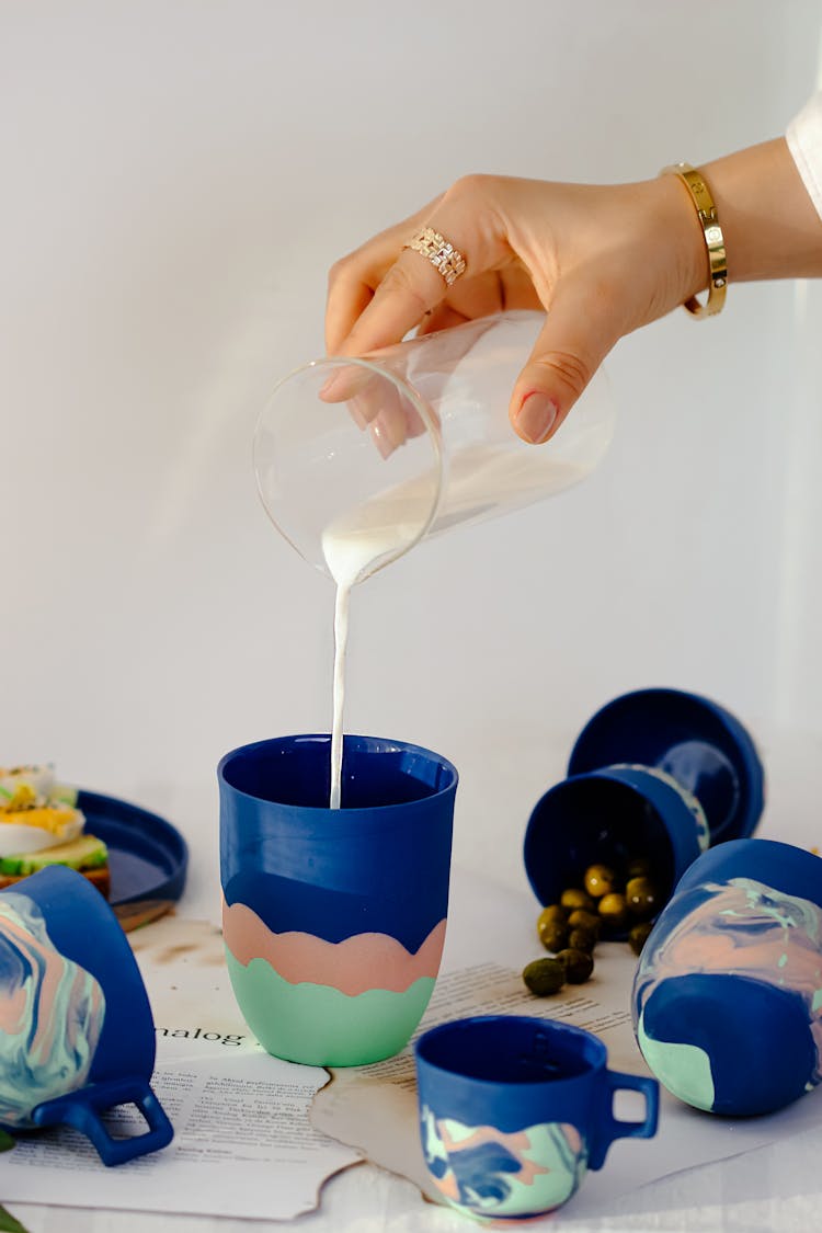 Woman Hand Adding Milk To Cups