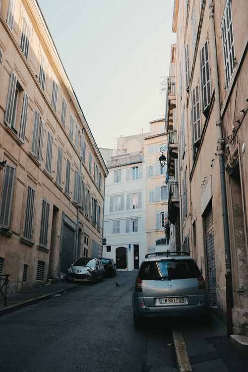 Free Picturesque narrow street with historic buildings and parked cars in a European town. Stock Photo
