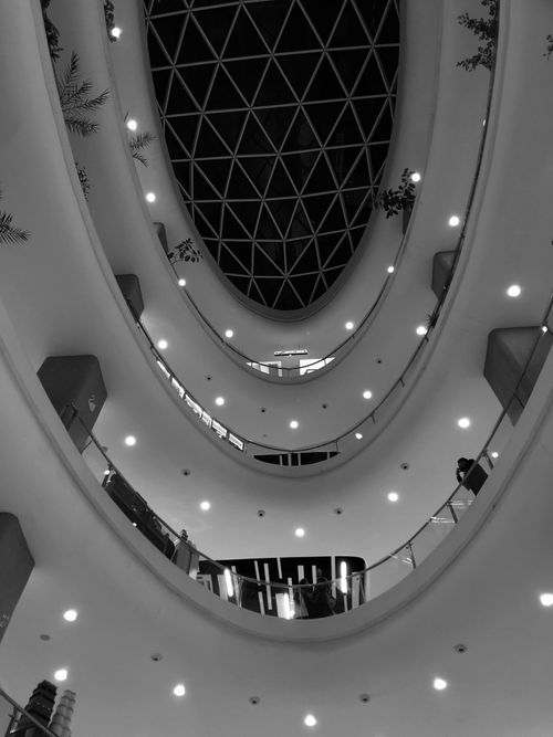 Free Low angle view of a contemporary shopping mall's interior with geometric ceiling. Stock Photo