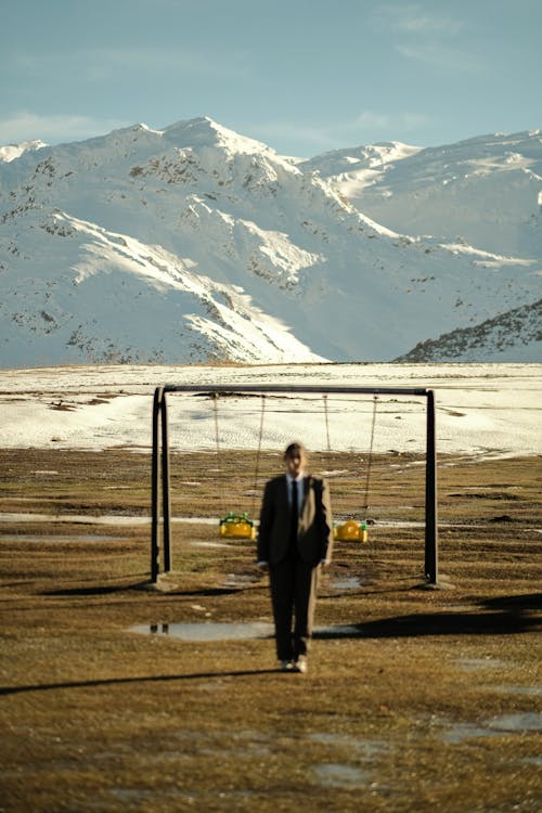 Person in a Suit Standing on a Field with Mountains in the Background 