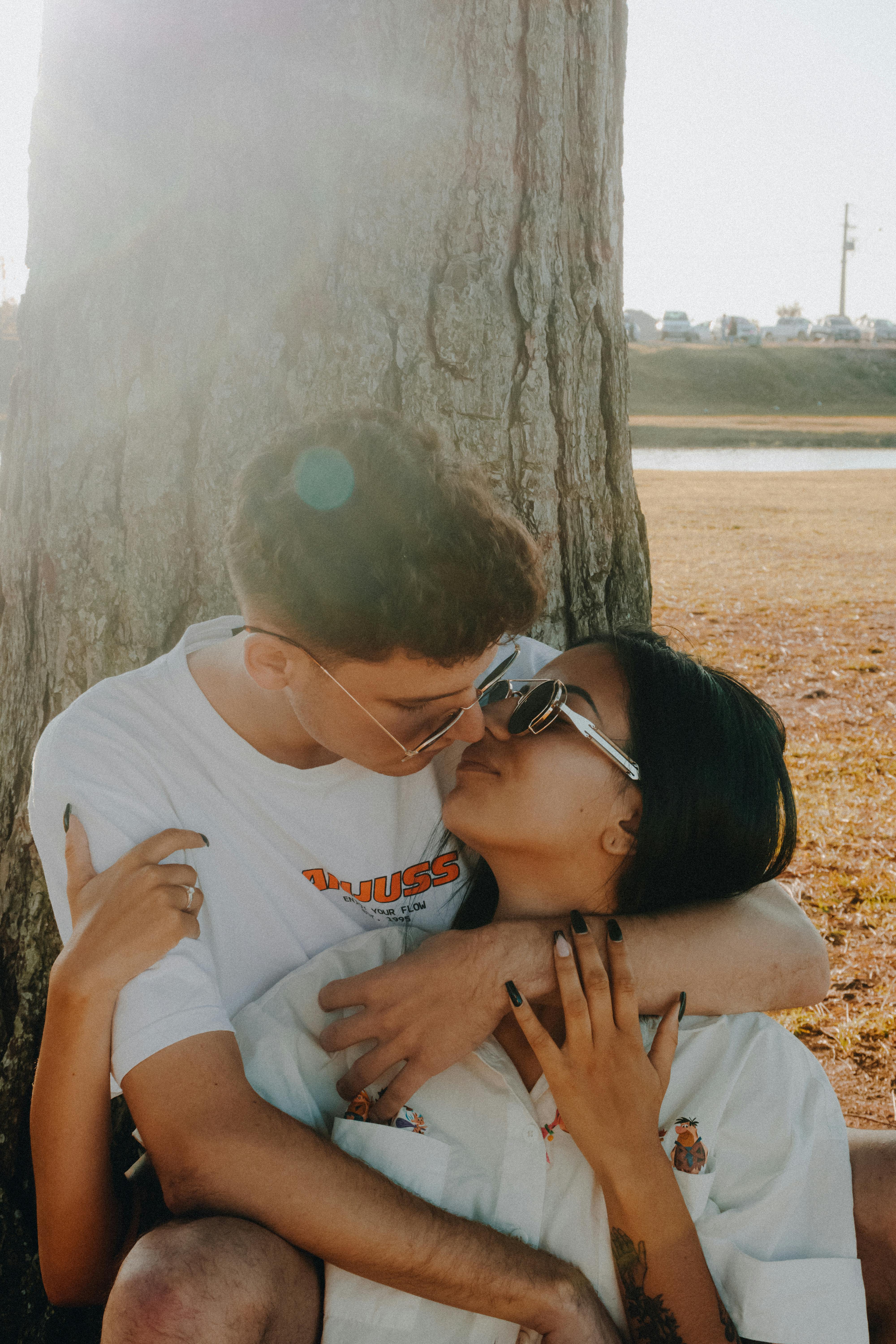 Young Couple Embracing by Tree on Beach · Free Stock Photo