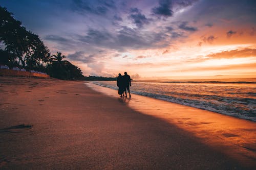 Dua Orang Berjalan Di Tepi Laut