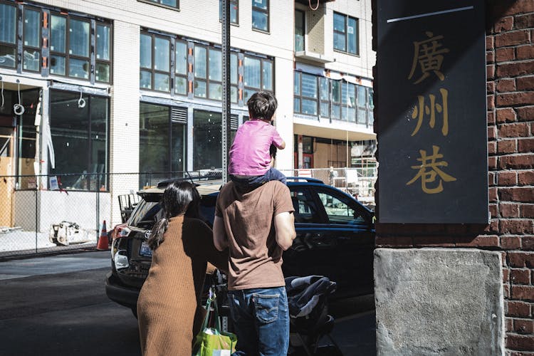 Father Carrying Child And Walking With Woman In Town