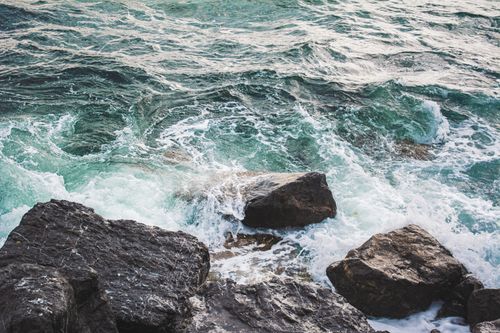 Free Waves crashing against rugged coastal rocks, showcasing the power of the sea. Stock Photo