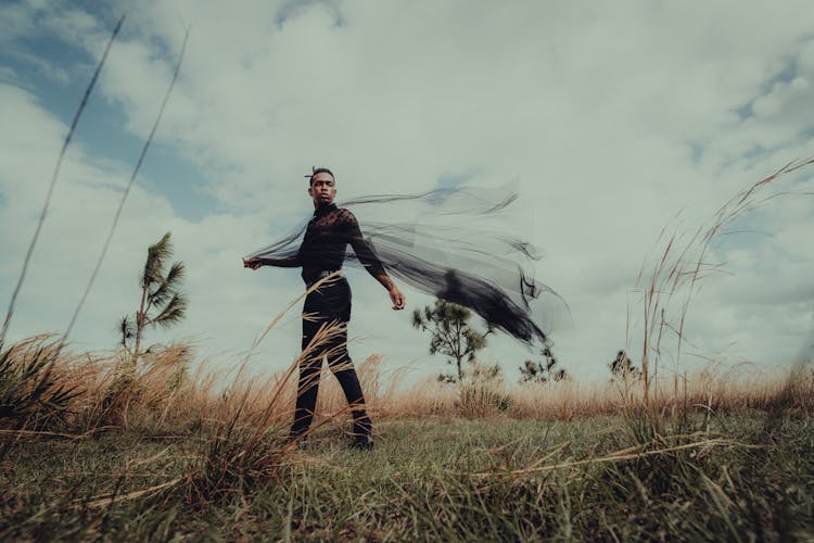 Man Standing On Grass And Waving With Black Fabric