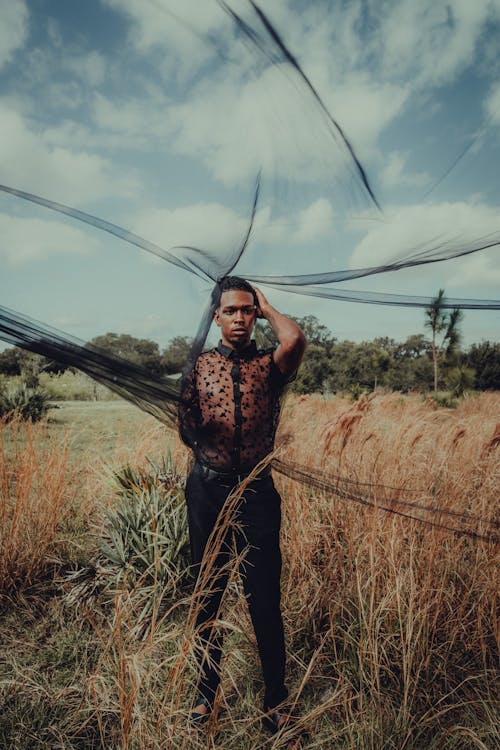 Man Standing on Grass with a Black Net Veil over Head