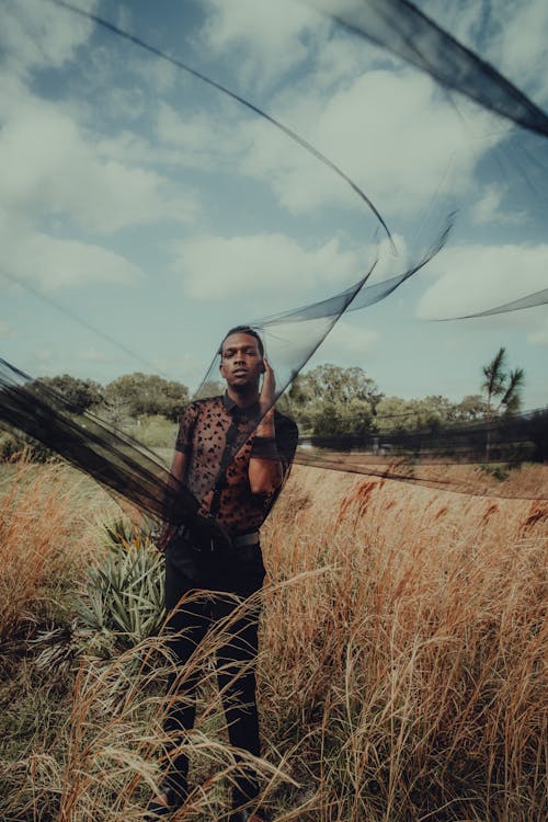 Standing Man on Grass Covering Face with Black Veil