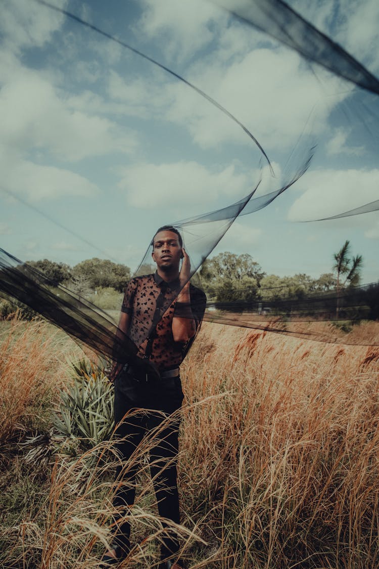 Standing Man On Grass Covering Face With Black Veil