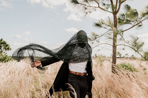 Man Walking on Meadow with Covered Face with Black Fabric