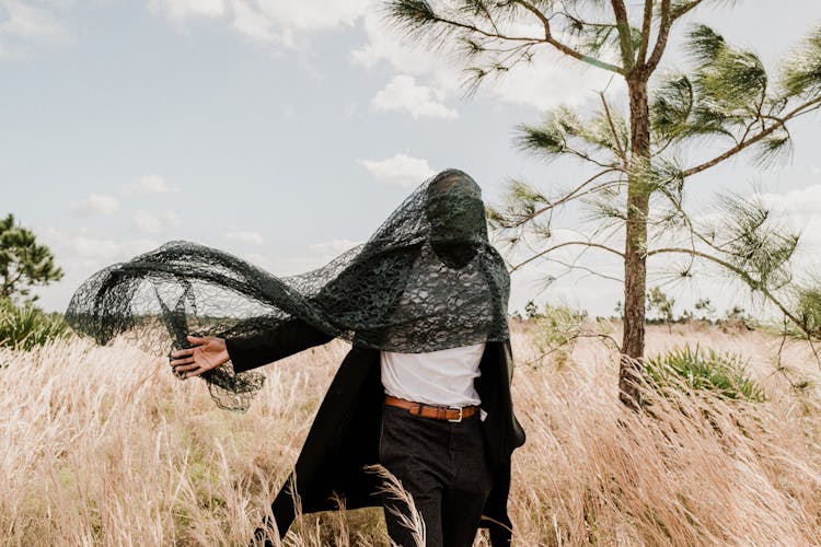 Man Walking On Meadow With Covered Face With Black Fabric