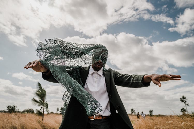 Man With Hands Stretched Out And Face Covered With Openwork Fabric