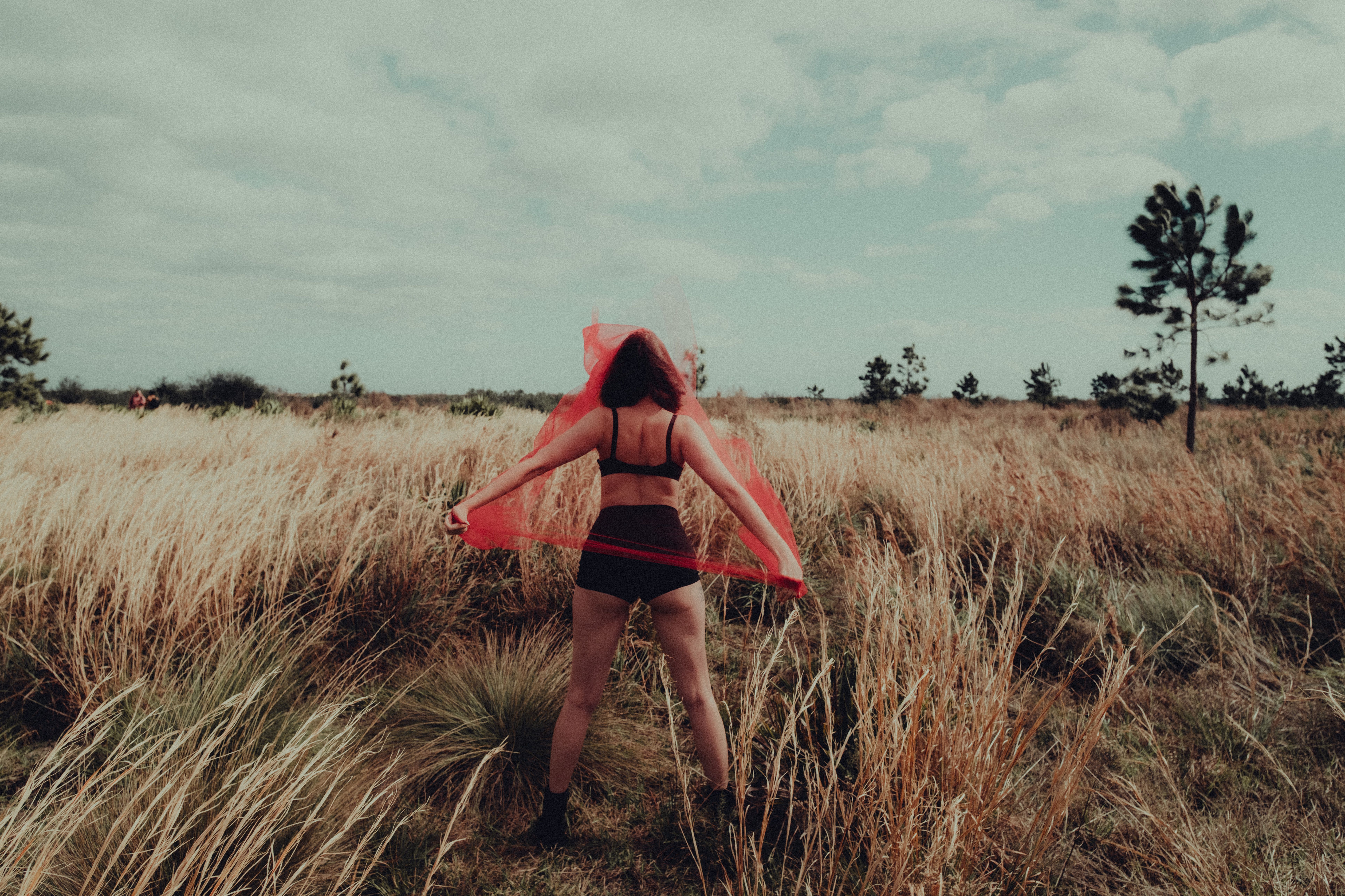 A woman in a red bikini is standing in a field · Free Stock Photo