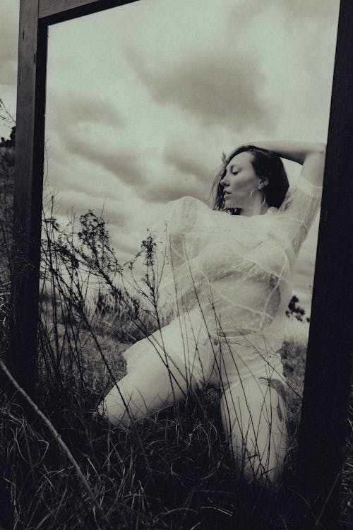 Black and White Photo of a Mirror Reflection of a Woman Posing on a Meadow 