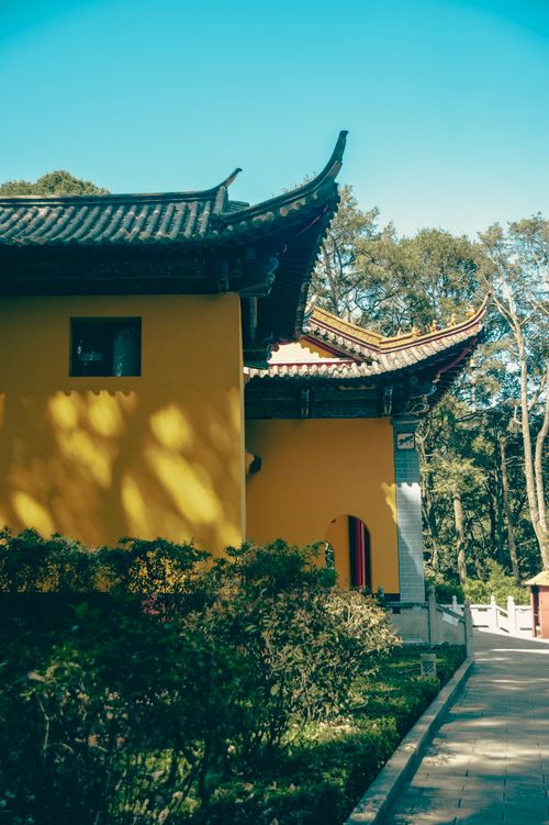 Free A vibrant yellow building with traditional Eastern architecture set in a lush garden under a clear blue sky. Stock Photo