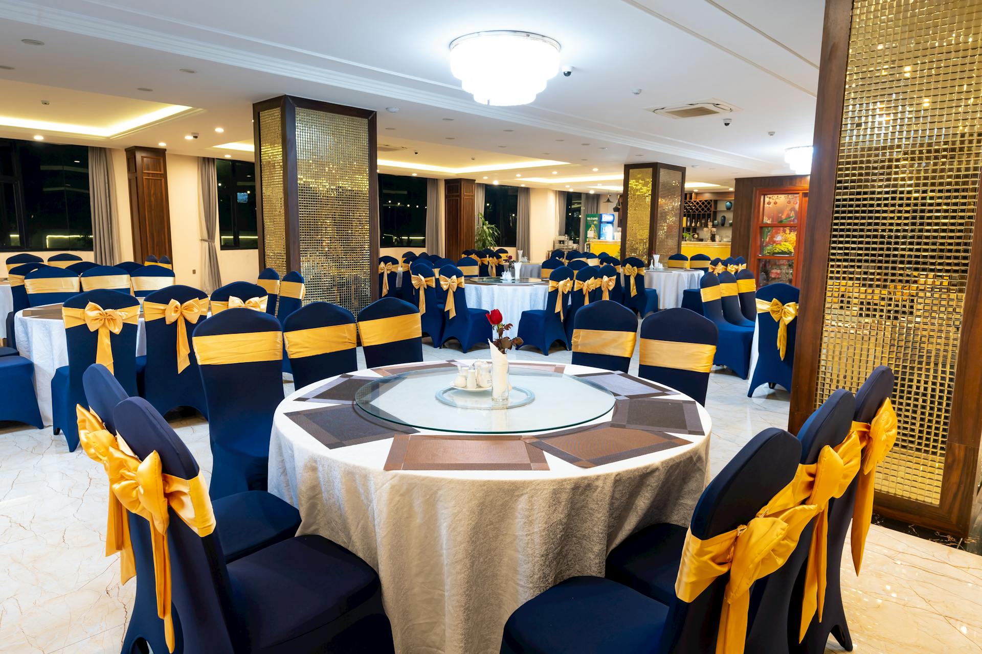 Luxurious banquet hall prepared for a formal event with elegantly set tables and chairs.