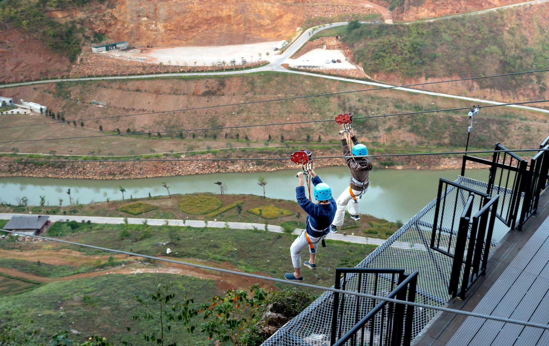 Two people zip lining over a picturesque valley, capturing the thrill of adventure sports.