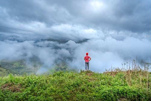 Person Standing in Mountains under Clouds