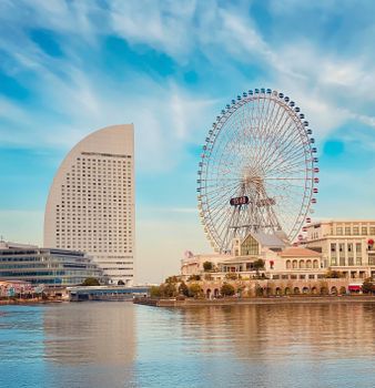 Modern architecture and Ferris wheel reflection in Yokohama, Japan's urban landscape.