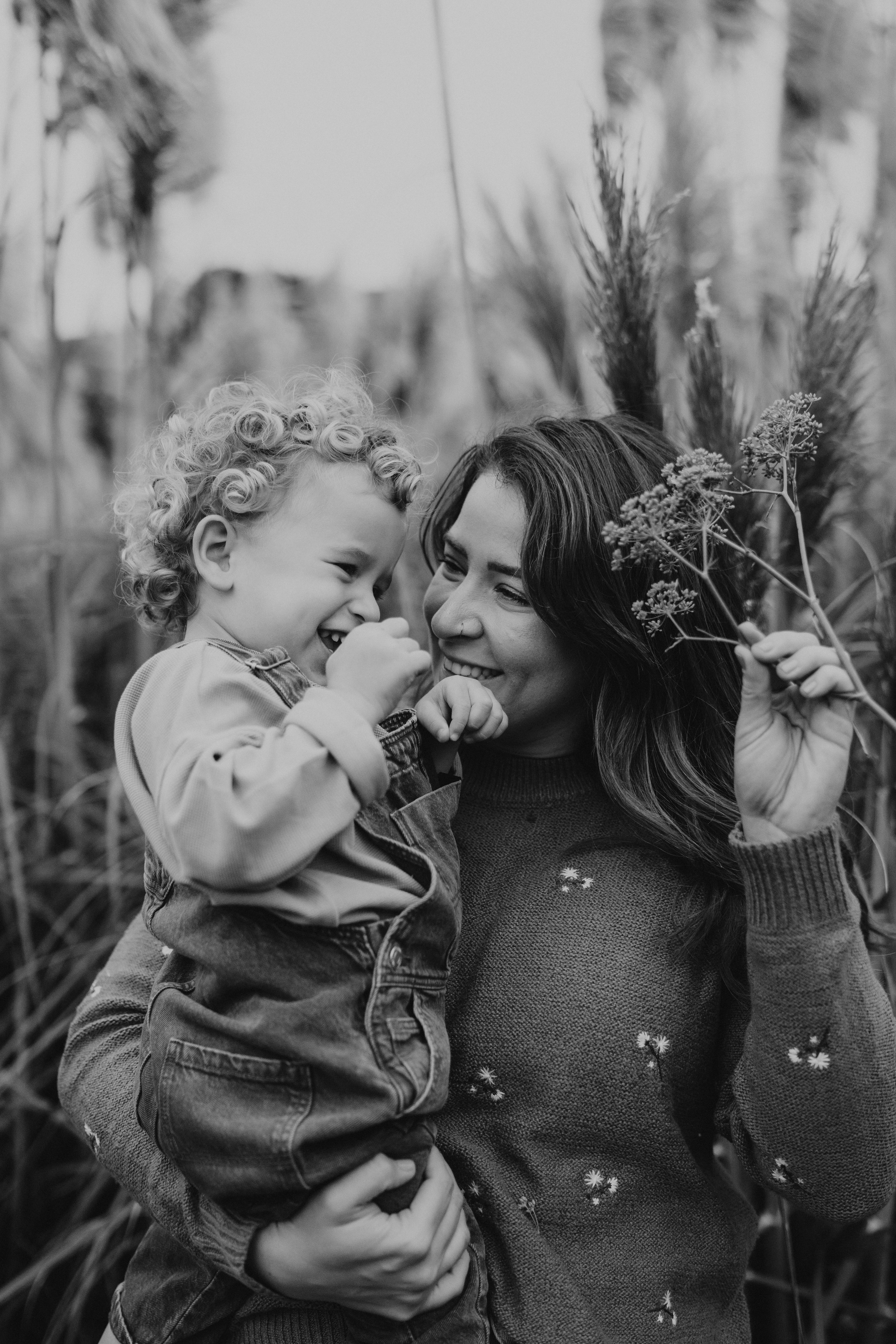 Heartwarming black and white portrait of a smiling mother holding her cheerful child amidst nature.
