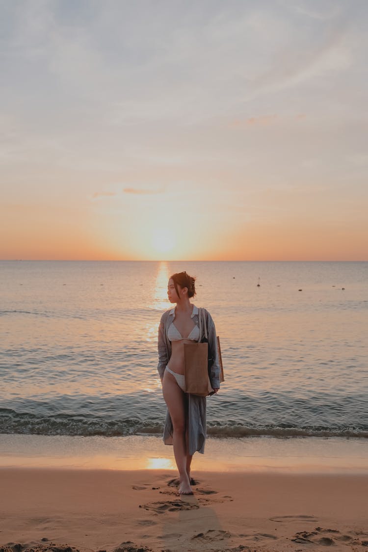 Woman Walking On A Beach At Sunset 