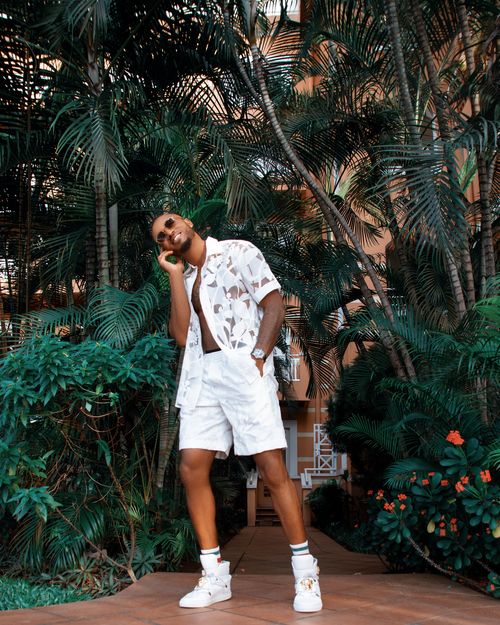 Free Man poses in trendy summer outfit amidst a lush tropical garden. Stock Photo