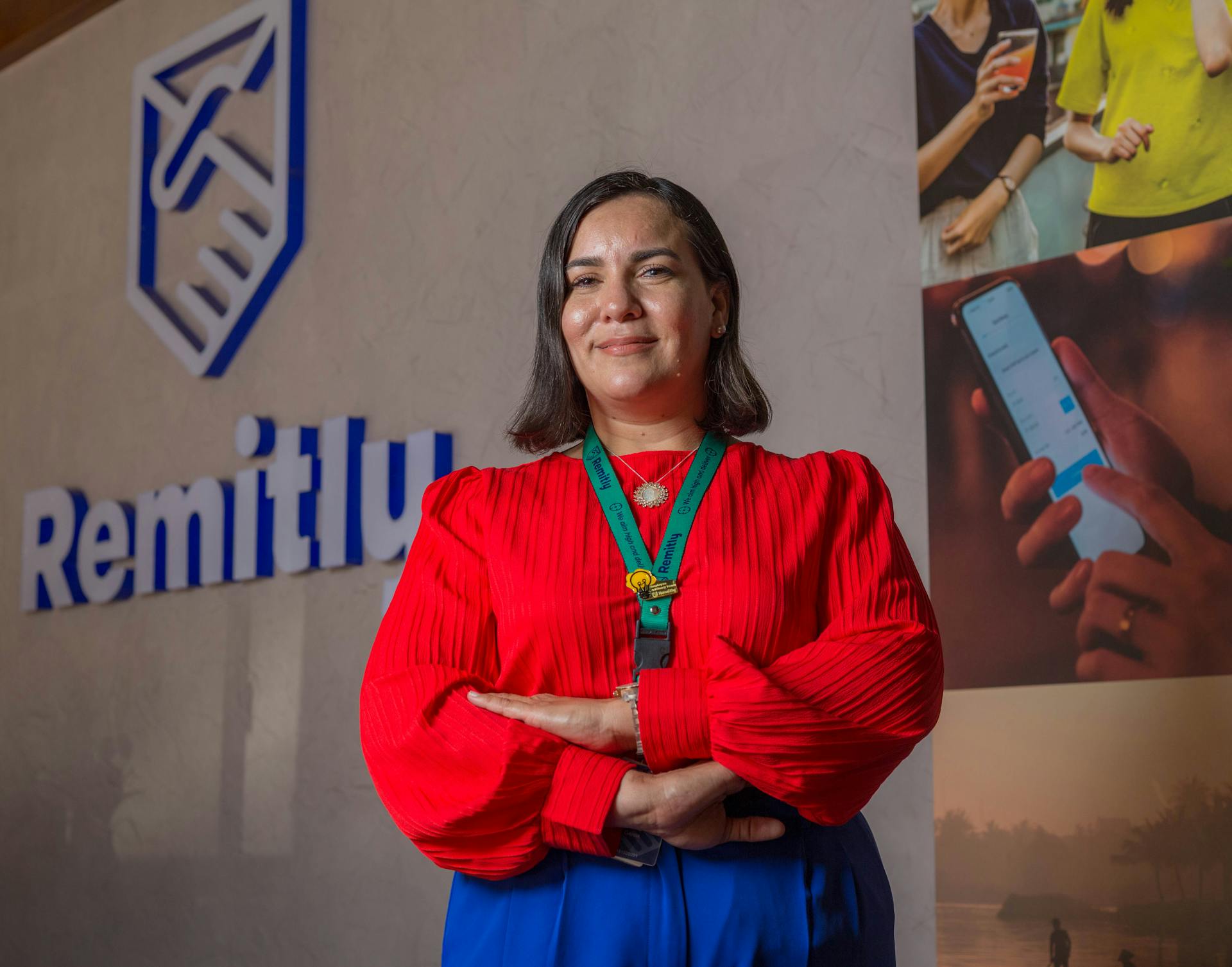 Professional woman in red, arms crossed, in front of Remitly logo in Managua, Nicaragua.