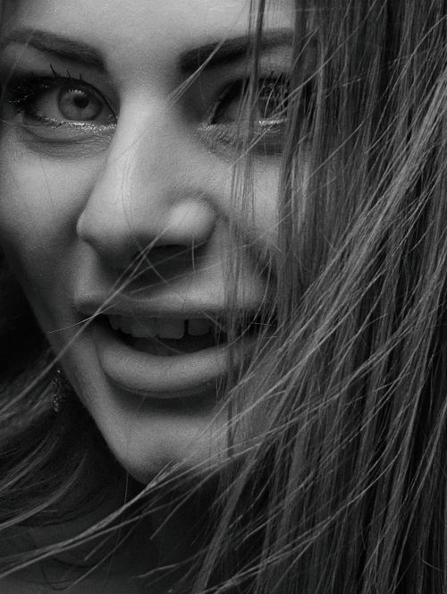 Free Expressive black and white portrait of a smiling woman with hair partially covering her face. Stock Photo