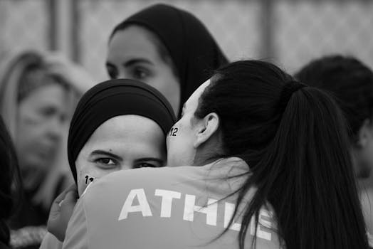 A group of young women wearing hijabs, embracing and smiling outdoors.