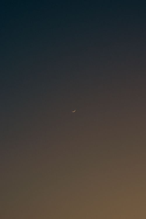 Free A serene view of a crescent moon against a tranquil evening sky, perfect for peaceful themes. Stock Photo