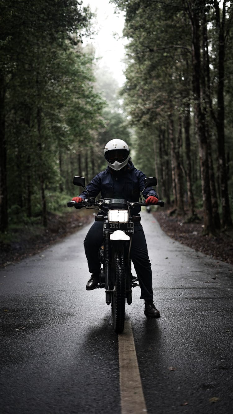 Man In Helmet Riding Bike On Road In Forest