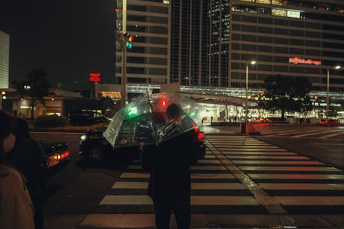 Man with Umbrella Walking on Crossing in Night City
