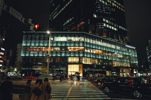 Bustling crosswalk scene in a vibrant downtown district, illuminated by city lights at night.