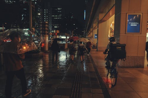 People Walking with Umbrellas in City in the Evening 