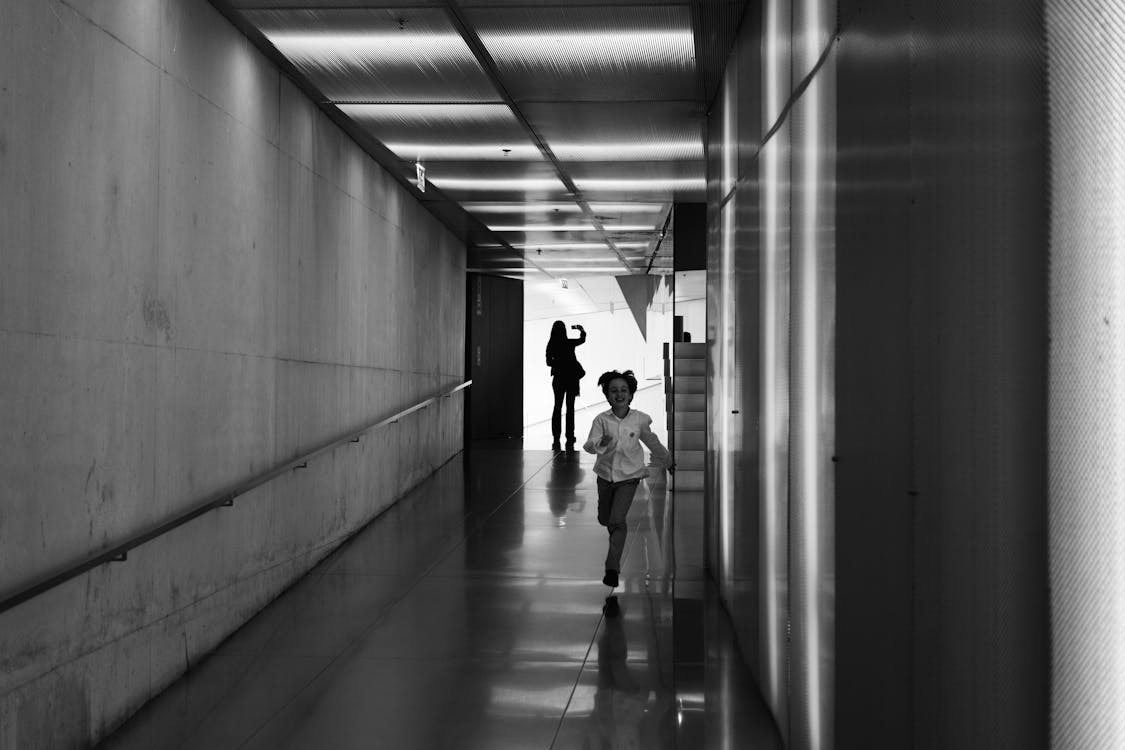 Person Running on Hallway Grayscale Photo