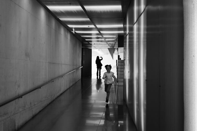 Person Running On Hallway Grayscale Photo