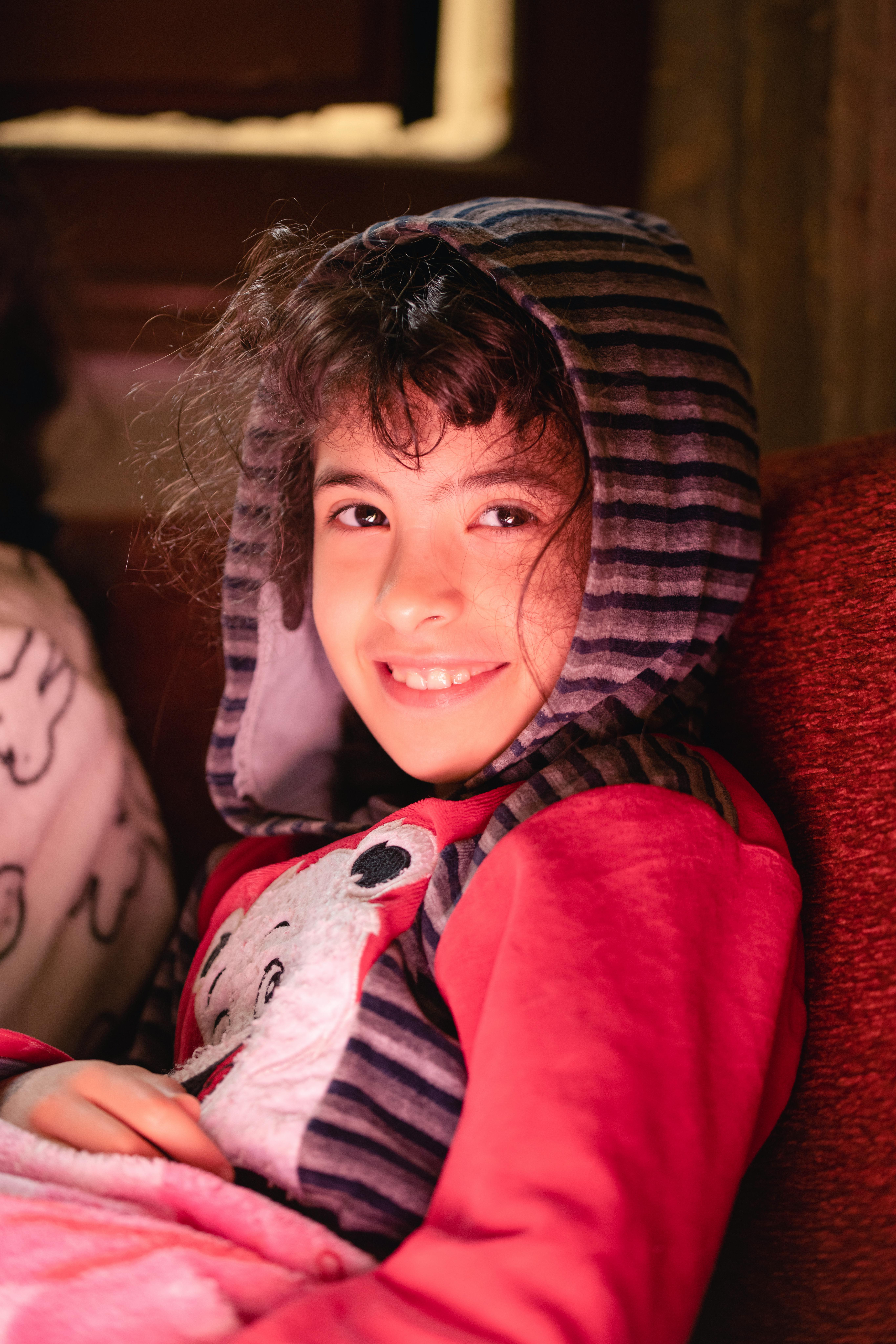 Smiling Girl in Hoodie Sitting on Sofa · Free Stock Photo