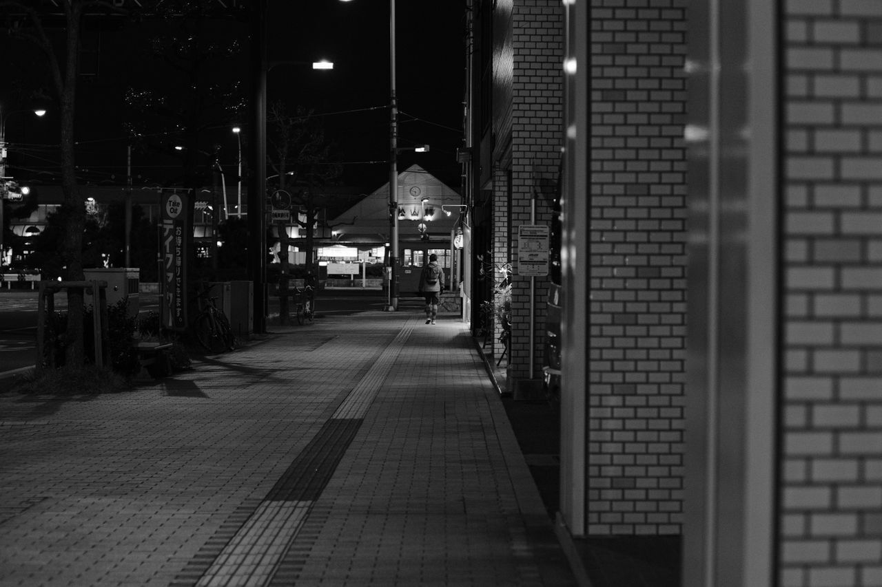 black and white city street at night with lights and shadows casting a