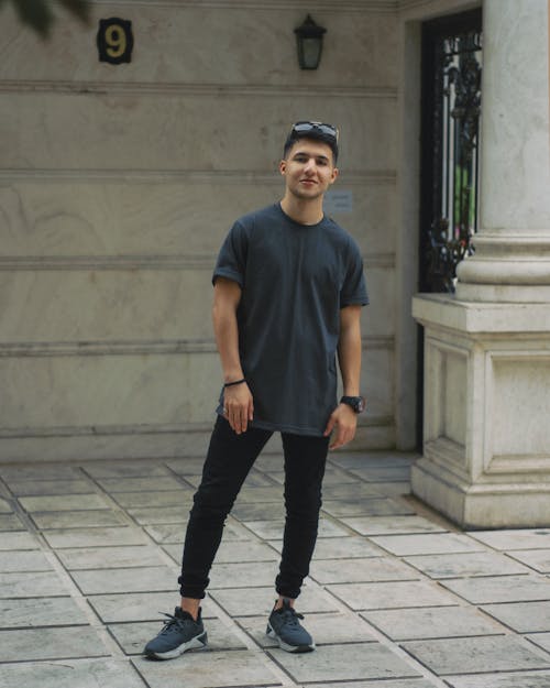 Young Man in a Casual Outfit Standing on a Sidewalk 