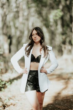 Young woman in elegant fashion posing confidently outdoors, showcasing modern style with natural backdrop.