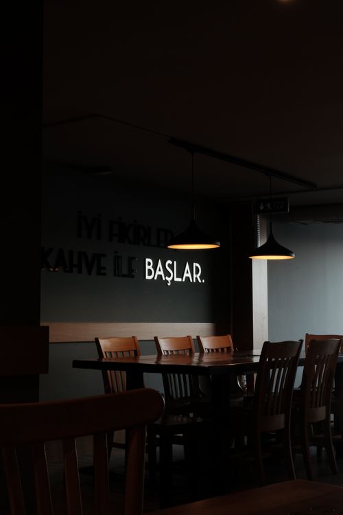 Free A dark, modern restaurant interior with wooden chairs and tables under pendant lighting. Stock Photo