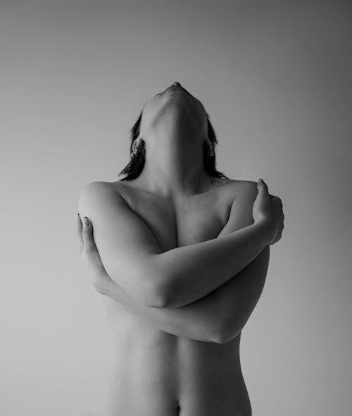 Black and White Photo of a Topless Woman Standing with Arms Crossed and Throwing Her Head Back 