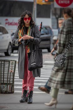 Stylish woman with camera on lively New York City street, showcasing urban fashion.