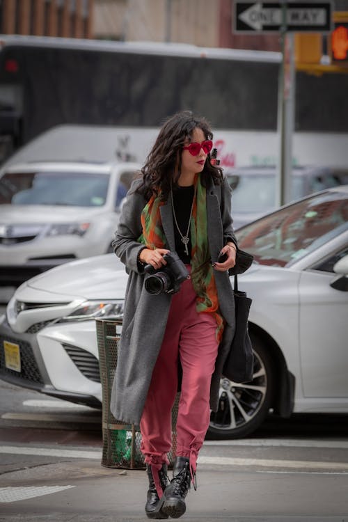 Fashionable Young Woman Walking on the Street with a Camera in Hand 